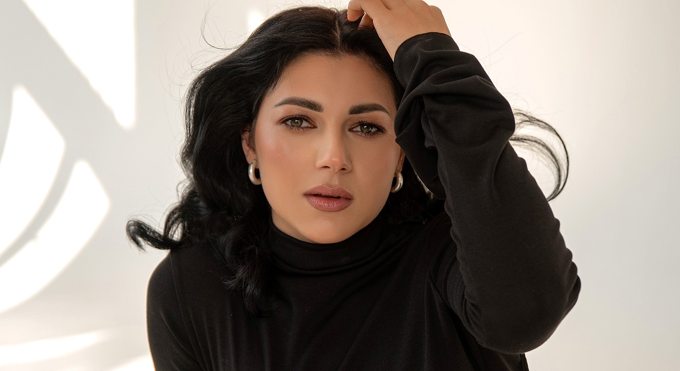Woman with dark hair in a black turtleneck.