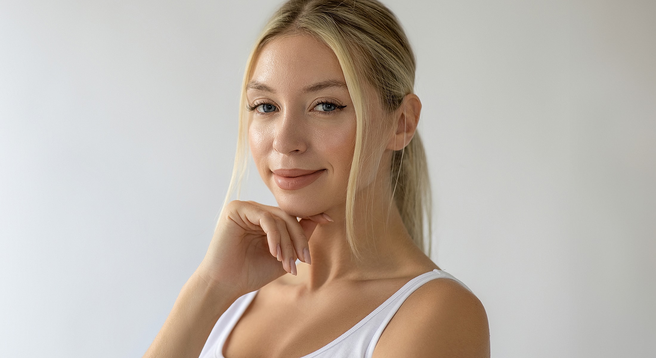 Young woman smiling with hand on chin.